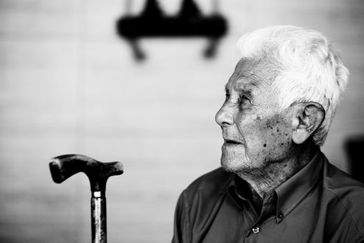 Elderly man in profile holding a cane, captured in black and white for timeless impact.