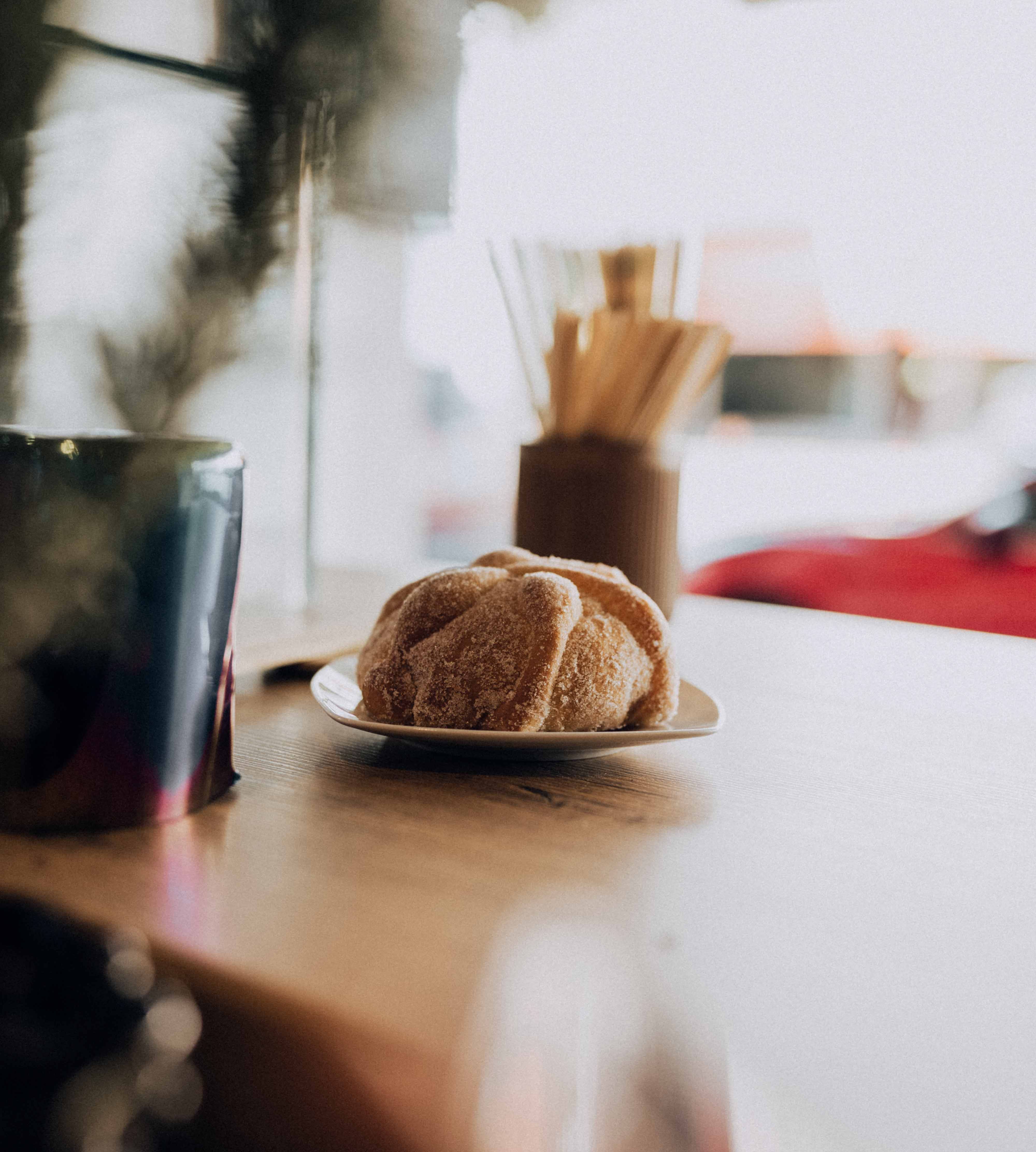 Warm café setting featuring a sugary pastry on a plate with a mug, ideal for cozy vibes.