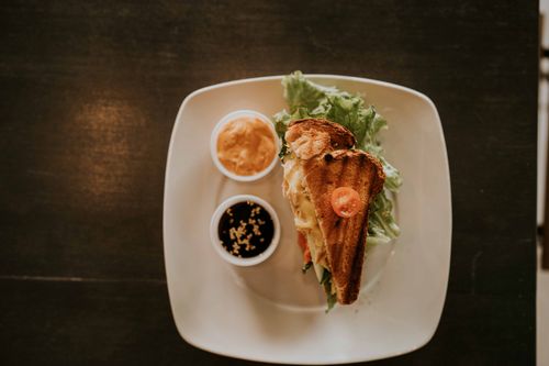 Free Top view of a grilled sandwich served with lettuce and sauces on a white plate. Stock Photo
