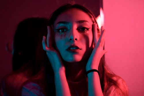 Free Close-up portrait of a woman with colorful dramatic lighting and expressive pose. Stock Photo