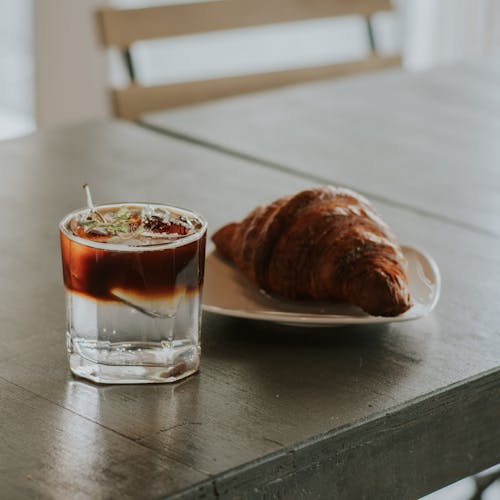 Cold Drink and Croissant Bread on Black Table