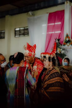 Karonese couple celebrates traditional wedding ceremony with vibrant attire indoors.