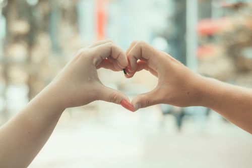 Free Two hands forming a heart shape in a warm outdoor setting, symbolizing love. Stock Photo