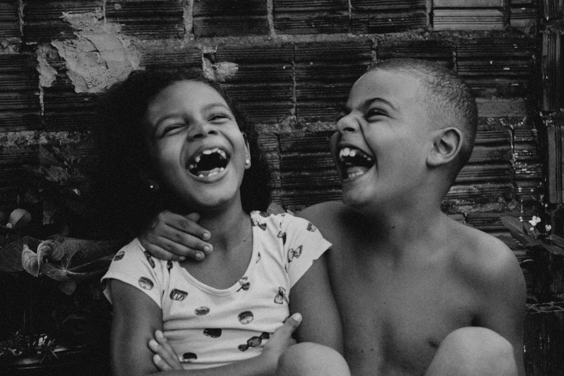 Black and white close-up of two children laughing joyfully together