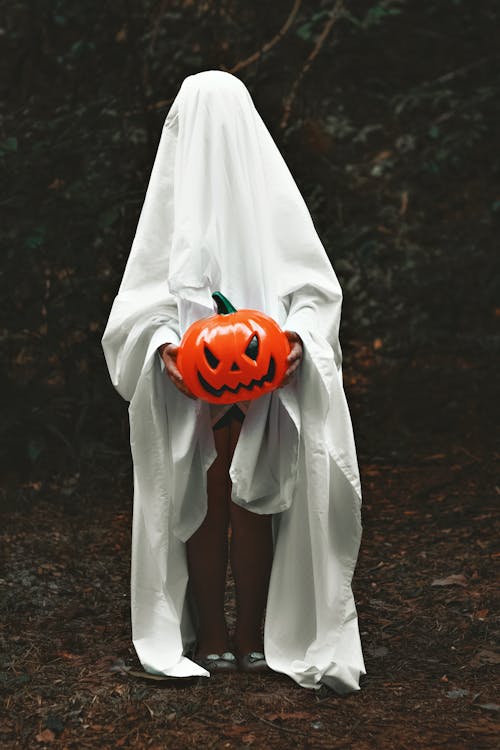 A Person Covered with a Blanket Holding a Plastic Pumpkin