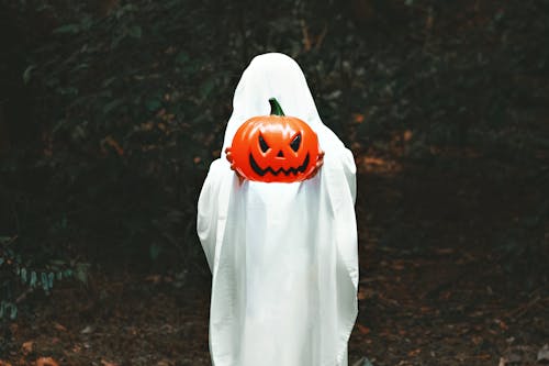 A Person Covered with a Blanket Holding a Plastic Pumpkin