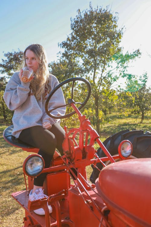 Free Woman in Blue Jacket Riding Red Tractor Stock Photo