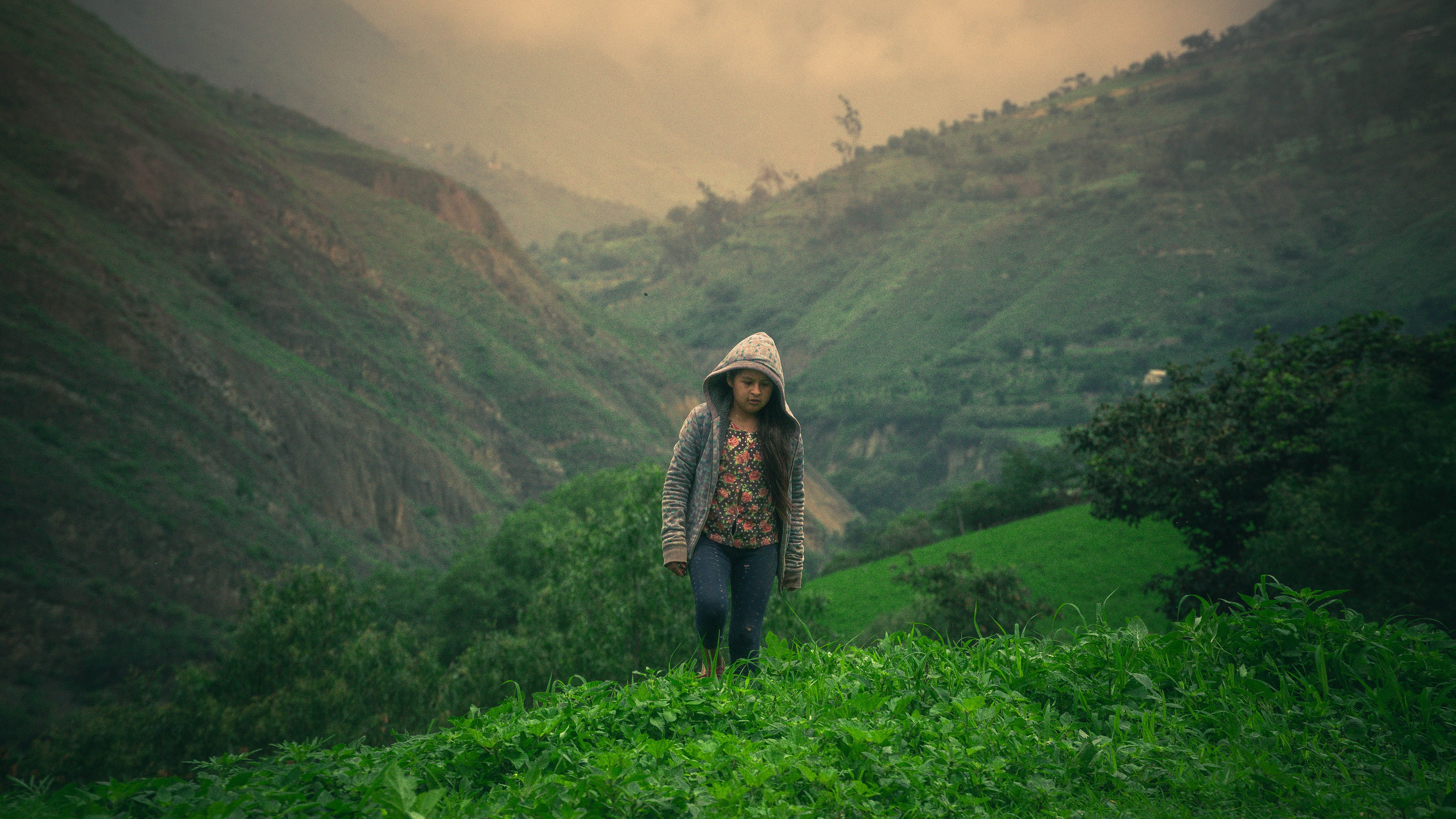 [ColoSach]-a-young-girl-in-a-hoodie-explores-the-picturesque-landscapes-of-huancavelica,-peru.