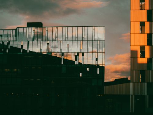 Free Reflections of city skyline on a glass building at sunset, showcasing modern architecture. Stock Photo