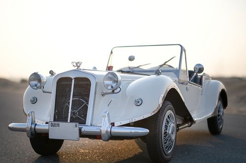 Free Classic white vintage convertible car showcased in a scenic desert backdrop in Dubai. Stock Photo