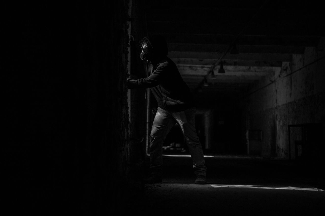 dramatic black and white photo of a man in a gas mask inside a dark ab