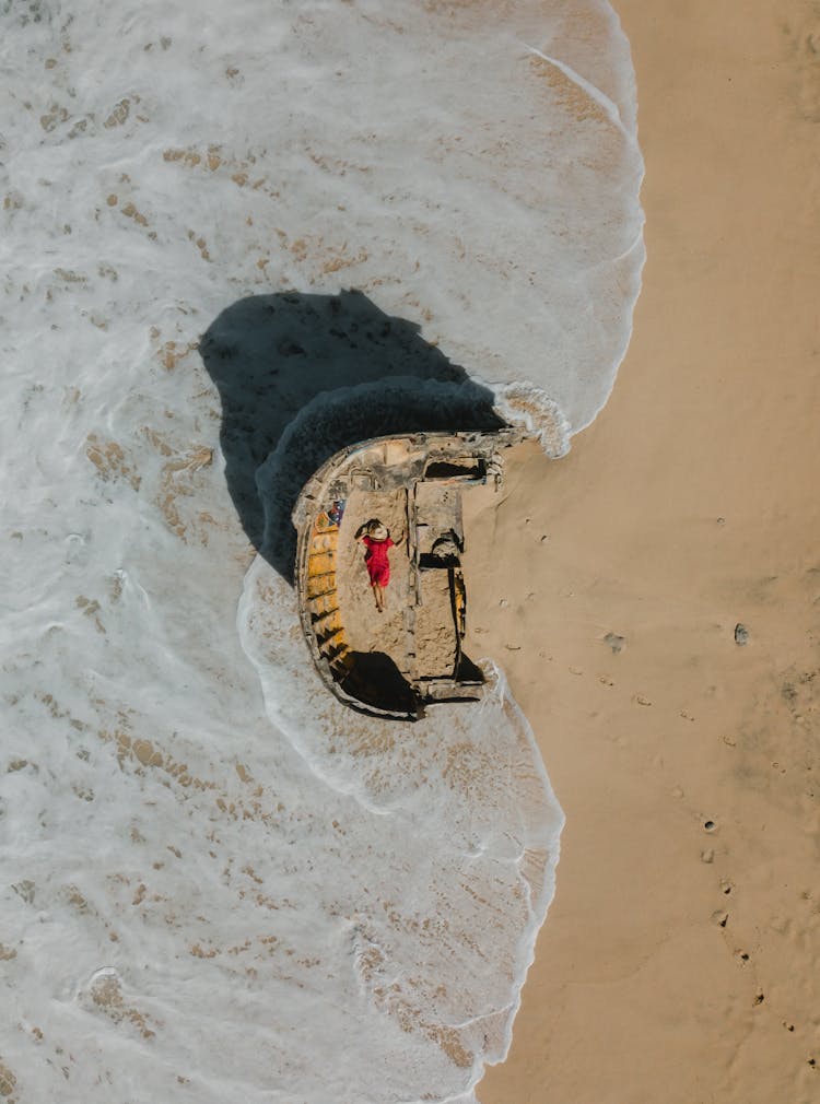 Abstract Photography Of A Woman Wearing A Red Dress Lying Down On Sand And Sea Foam Around 