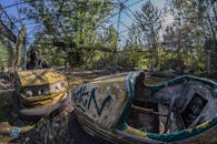 Two Wrecked White and Yellow Bump Cars Surrounded With Trees