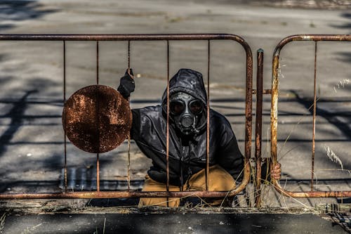 Persona Che Indossa La Maschera Antigas Seduta Dietro Il Recinto Di Metallo