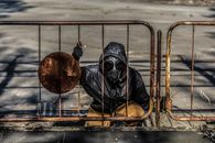 Person Wearing Gas Mask Sitting behind Metal Fence