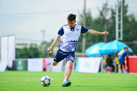 A young male soccer player kicks a ball on an outdoor field, showcasing athleticism and focus.