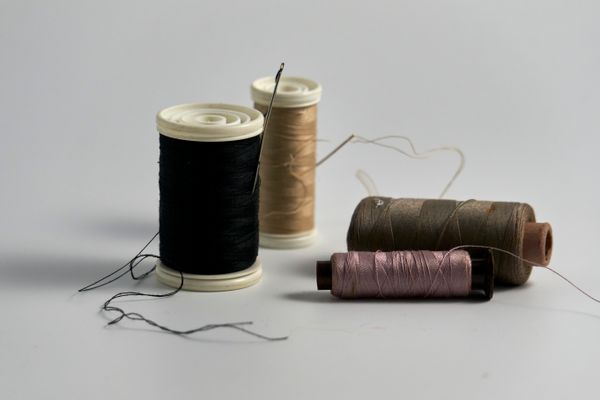 Spools of sewing thread and needles, photo by Richard REVEL on Pexels