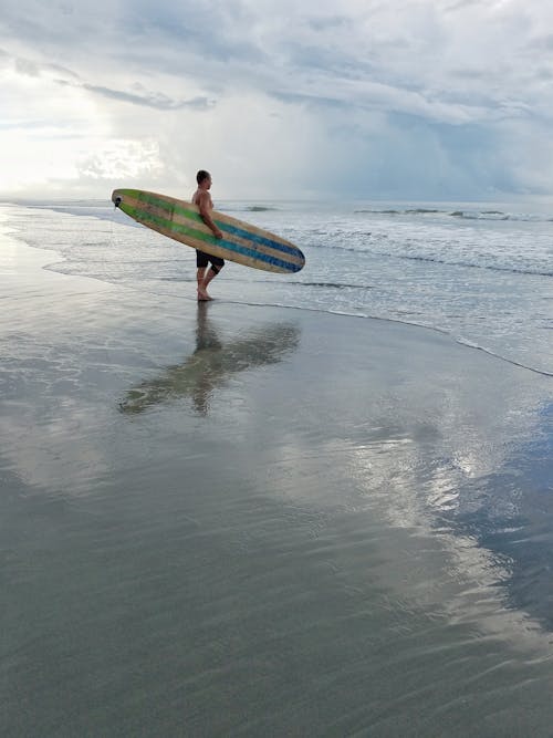 Mann, Der Surfbrett Hält, Während Er Auf Den Ozean Starrt