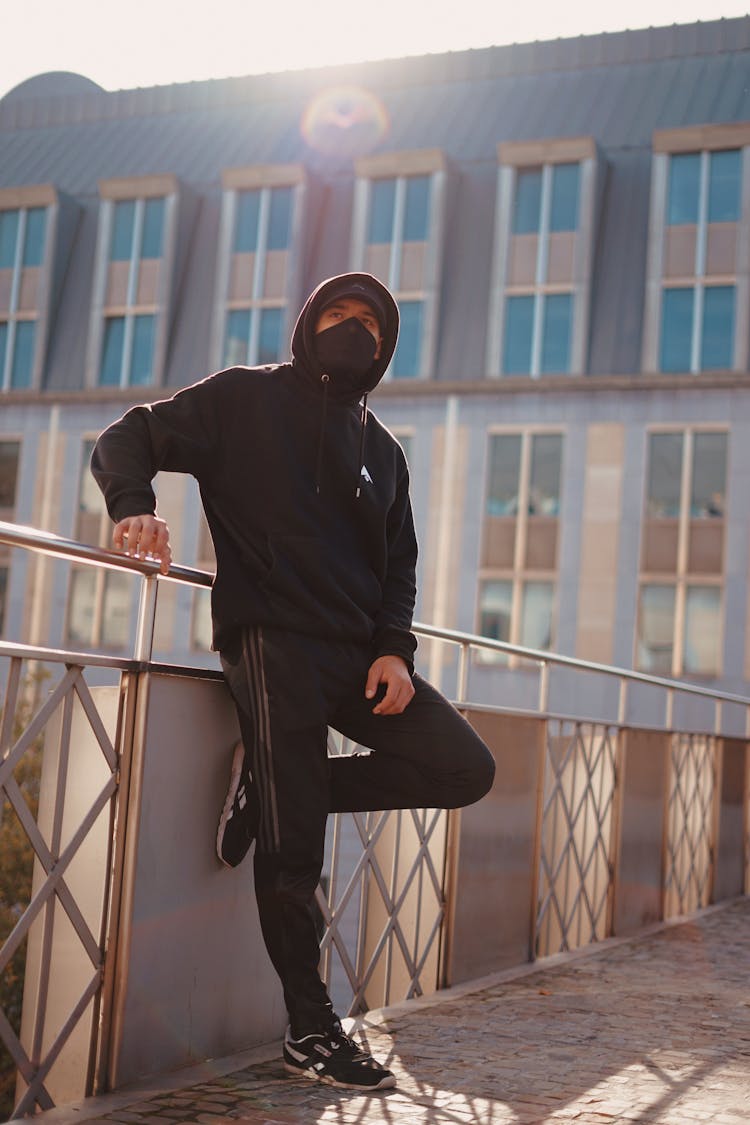 Man In Black Jacket Leaning On Metal Railings