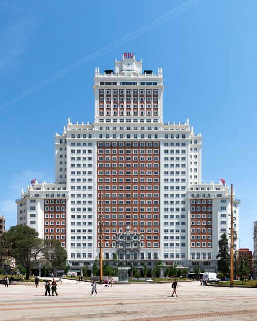 Free Front view of Hotel Riu Plaza in Madrid under a clear blue sky, capturing urban architecture. Stock Photo