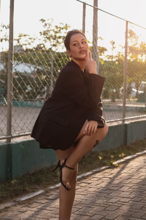 Free Fashionable woman in blazer striking a pose outdoors at sunset, showcasing bold style. Stock Photo