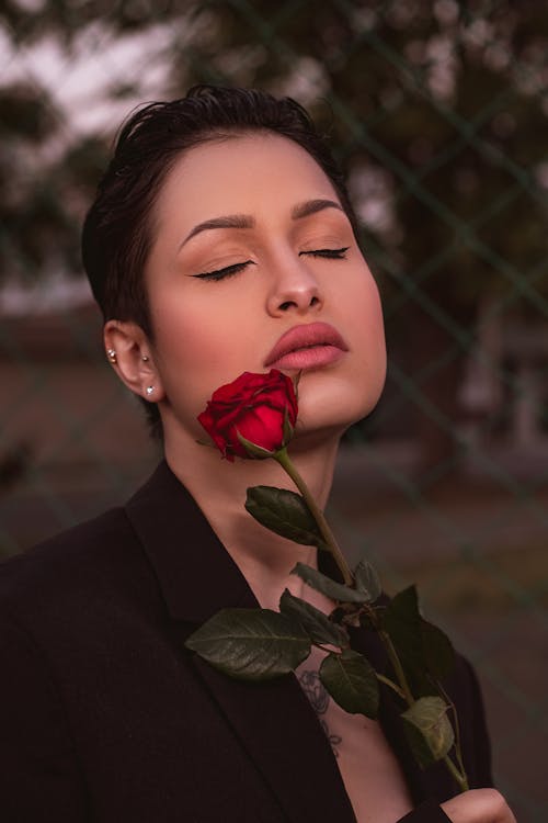A Woman Holding Red Rose While Eyes Closed 