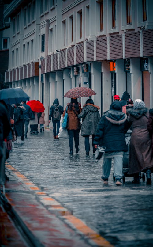 People Walking on Sidewalk with Umbrellas