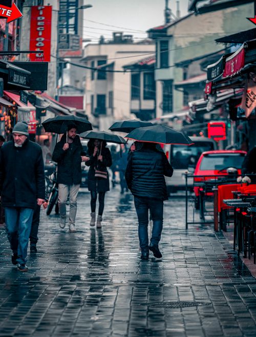 Free People with umbrellas walking down a rainy market street in Bursa, Turkey. Stock Photo