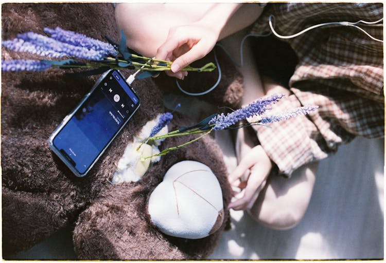 Woman With Wildflowers Listening To Music On Cellphone