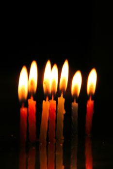 A close-up of colorful burning birthday candles against a dark background.