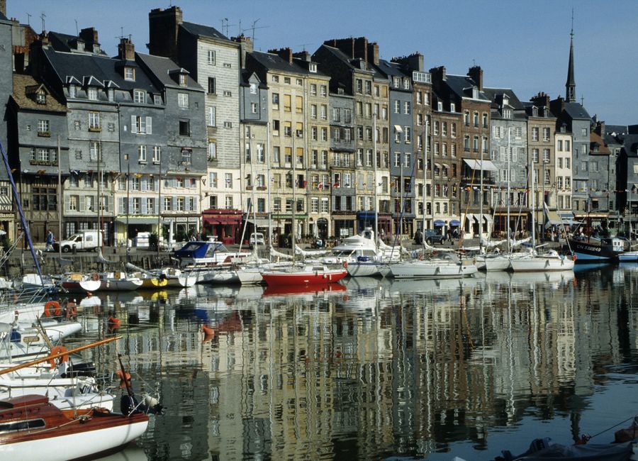 Charming boats docked by colorful historic buildings in Honfleur's Vieux Bassin, Normandy, France.