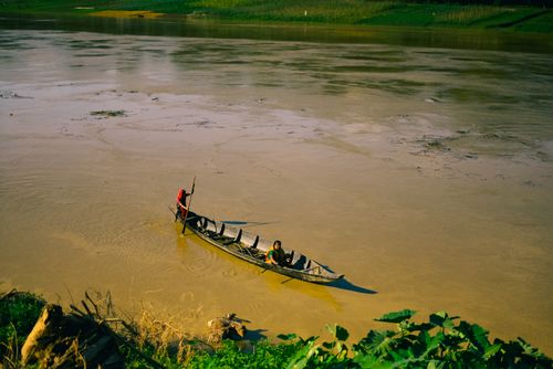 Free Scenic view of a traditional boat gliding peacefully along a calm river under a clear sky. Stock Photo