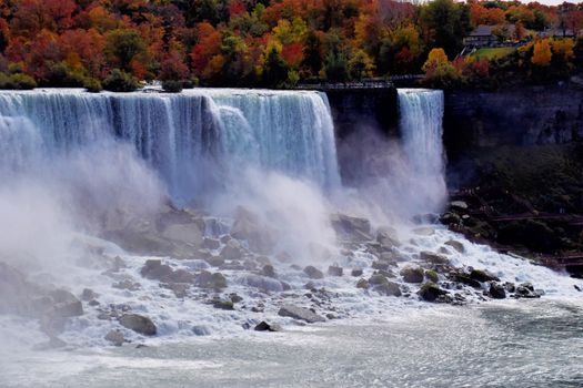 Capture of Niagara Falls framed by vibrant autumn foliage and rushing waters.