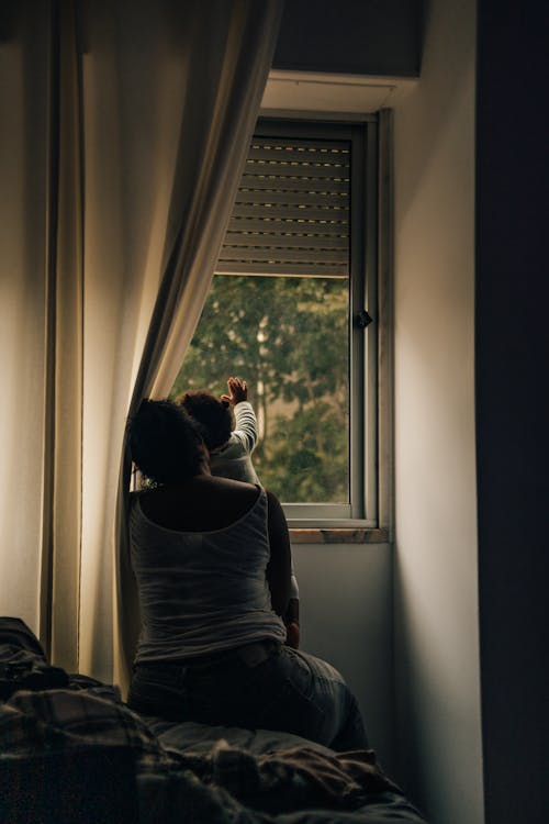 Woman and a Baby Looking through Bedroom Window