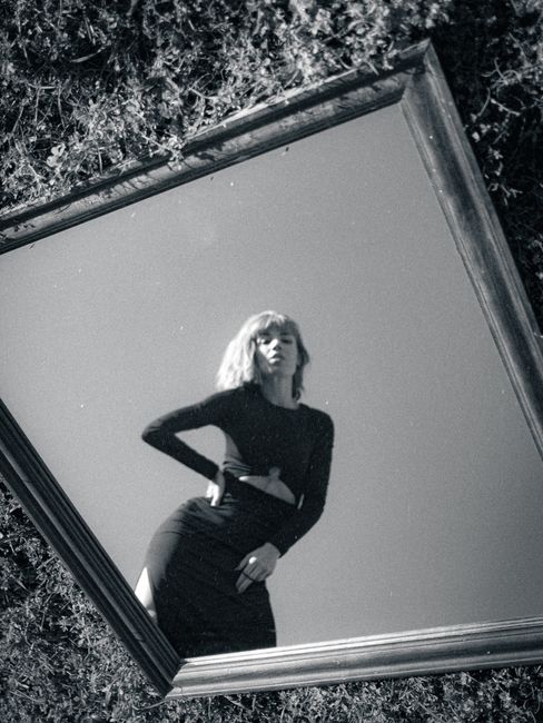Artistic black and white portrait of a fashionable woman in a mirror reflection.