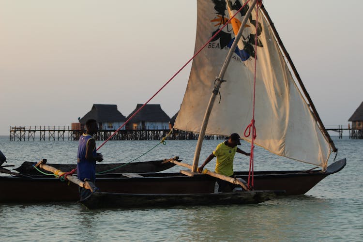 Photo Of Men Pushing A Sailboat