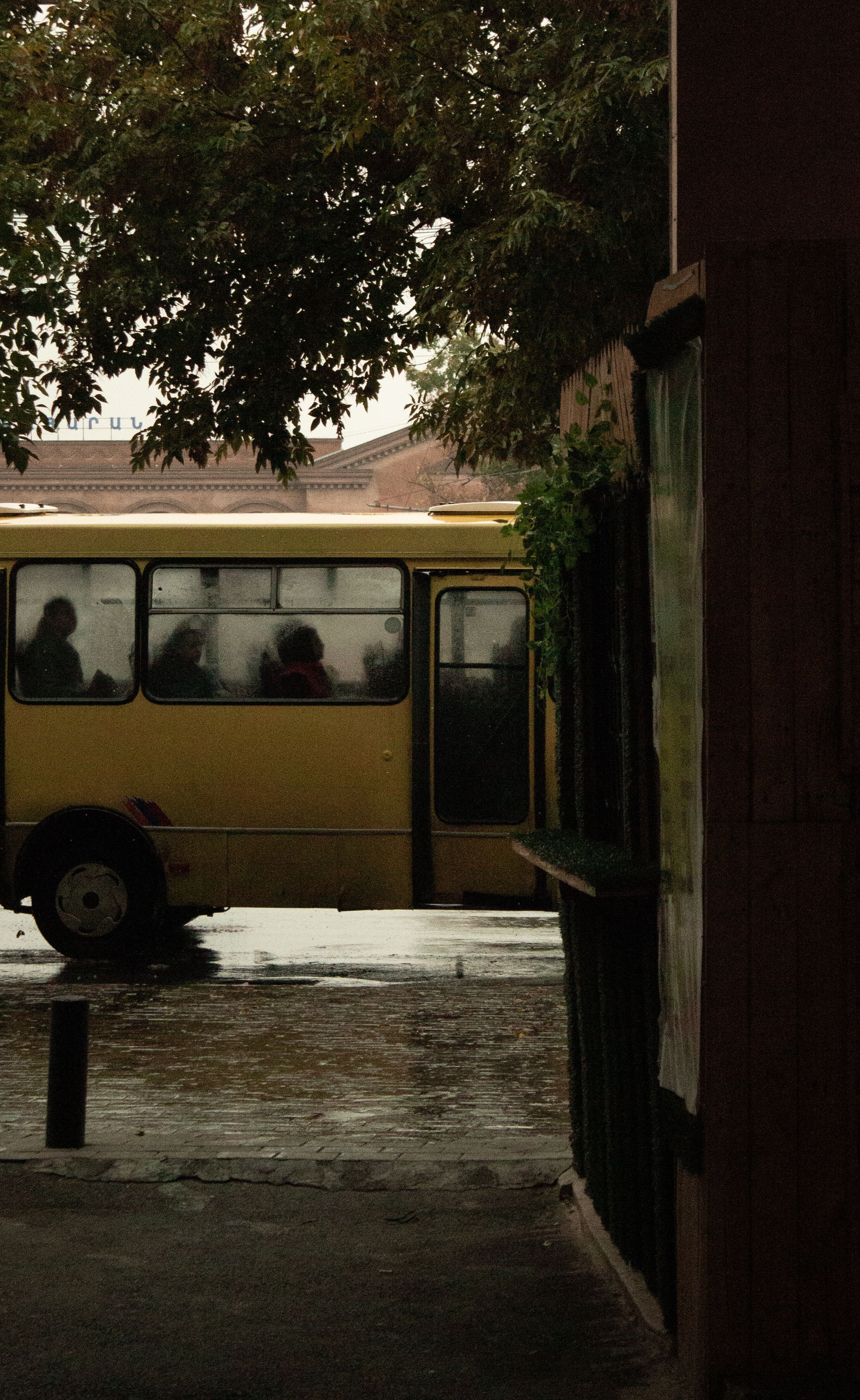 A yellow bus travels through a rainy street, capturing everyday commuting life.