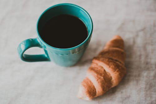 Free Teal Ceramic Mug Filled With Coffee Near Baked Bread Stock Photo