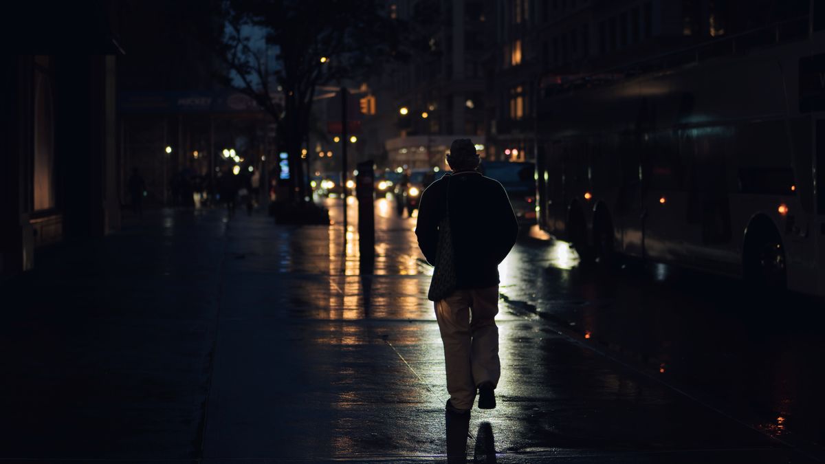 街灯に照らされた夜の通りを一人で歩く男性