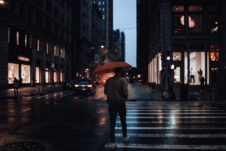 Man With Umbrella Crossing Street At Night