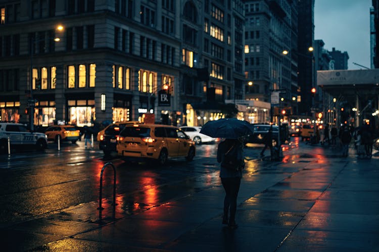 A Woman Walking On The Street During Night Time