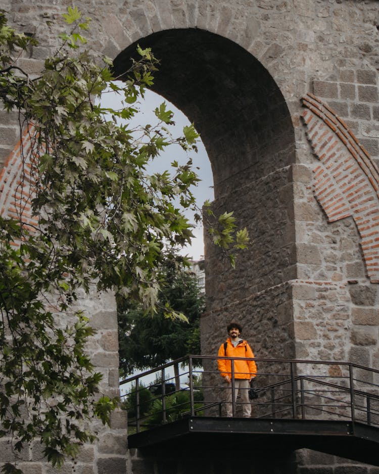 Man Standing On Bridge Near Brick Castle Arch