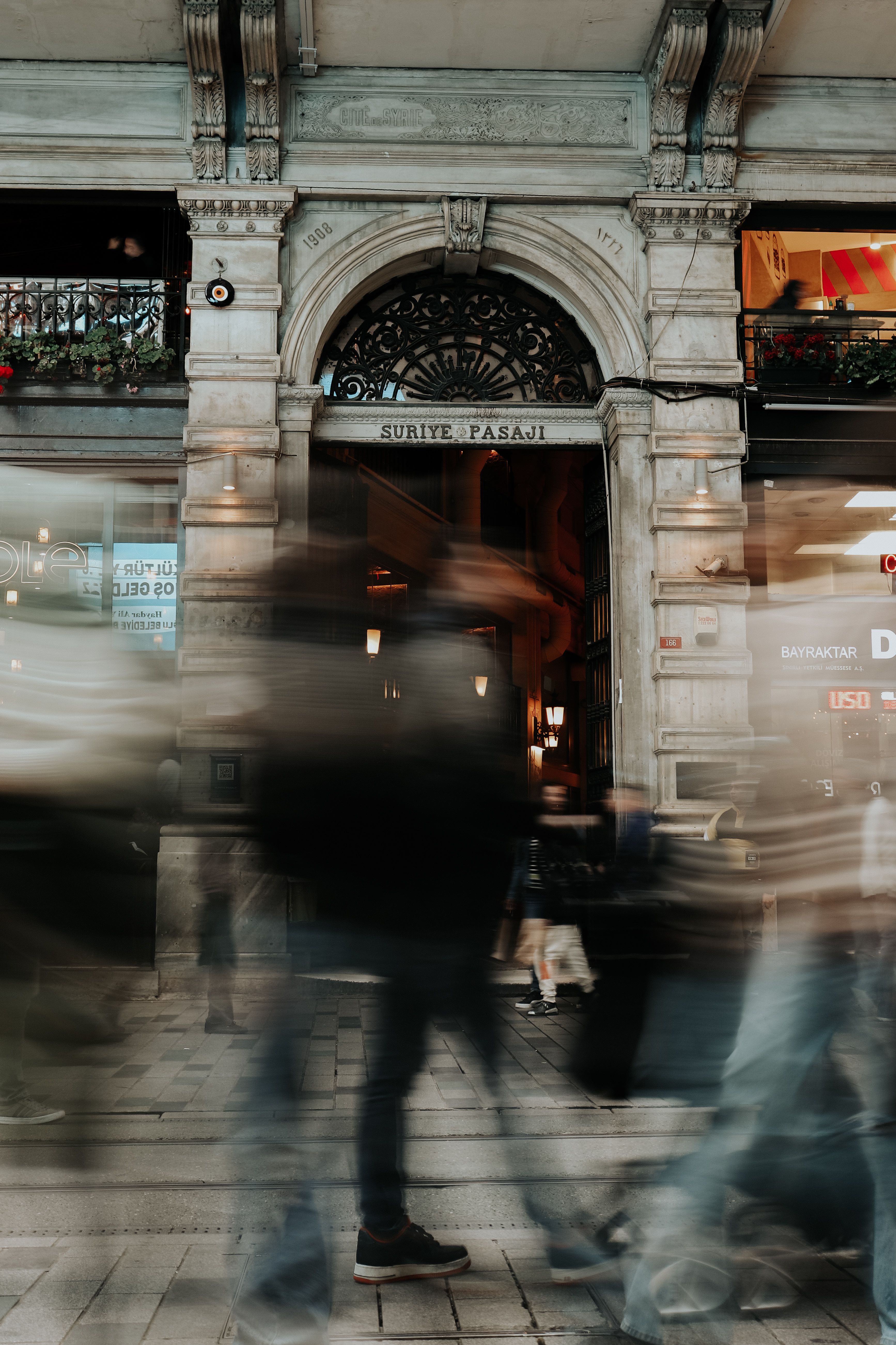 Dynamic urban scene capturing blurred pedestrians against Istanbul's historic Suriye Passage.