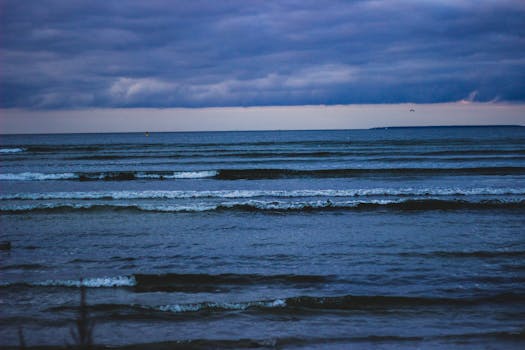 Capture of ocean waves under a dramatic, cloudy dusk sky. Perfect for nature lovers.
