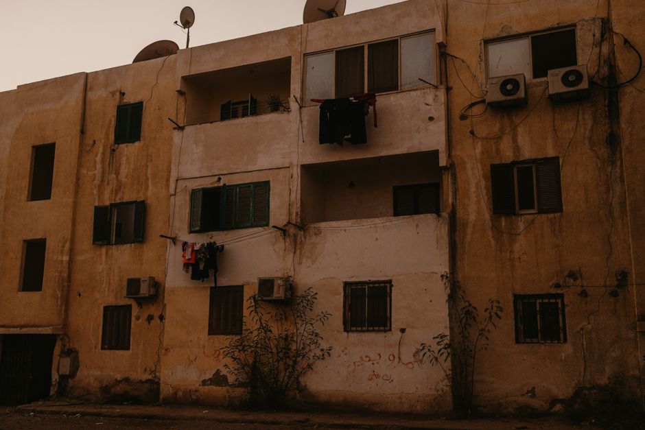 Weathered Mediterranean apartment building with water-stained, cracked render and damp-damaged facade