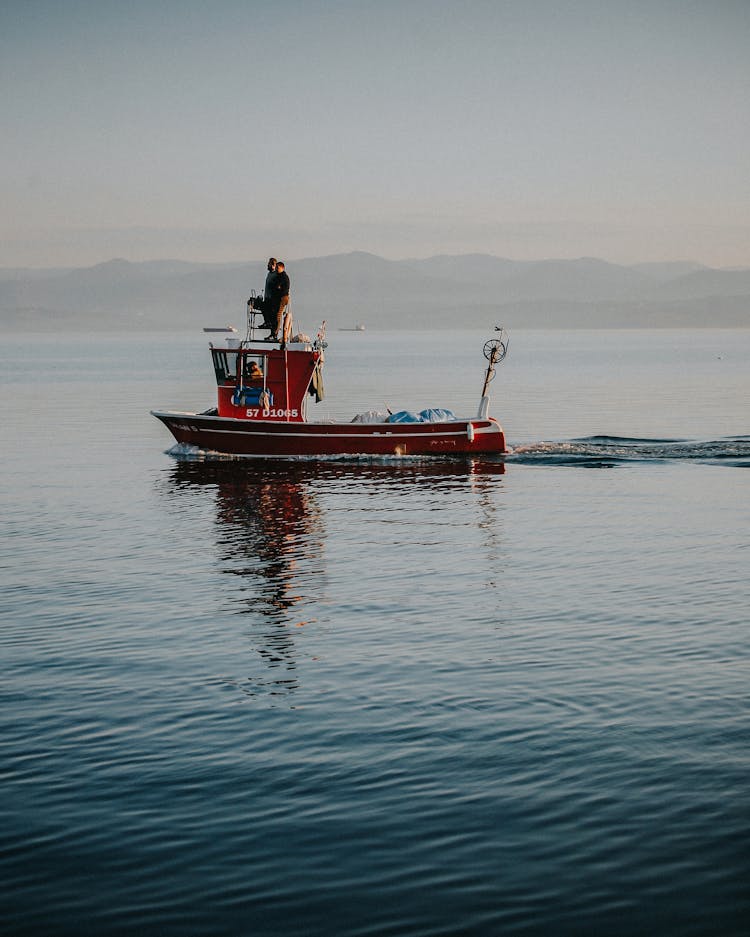 People On Small Fishing Boat Sailing On Lake