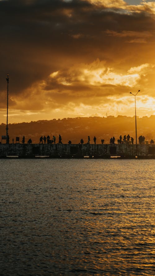 Silhouette of People on the Dock near Ocean during Sunset