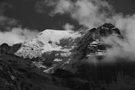 瑞士阿尔卑斯山的黑白照片中，白雪覆盖的山峰被云雾环绕