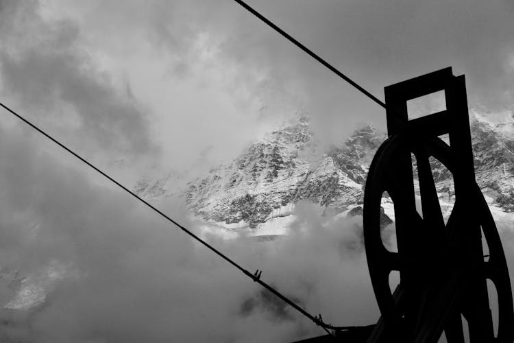 Grayscale Photography Of Pulley Near Mountain