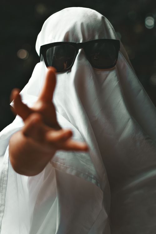 Free A person in a ghost costume wearing sunglasses reaches out in a playful manner. Stock Photo